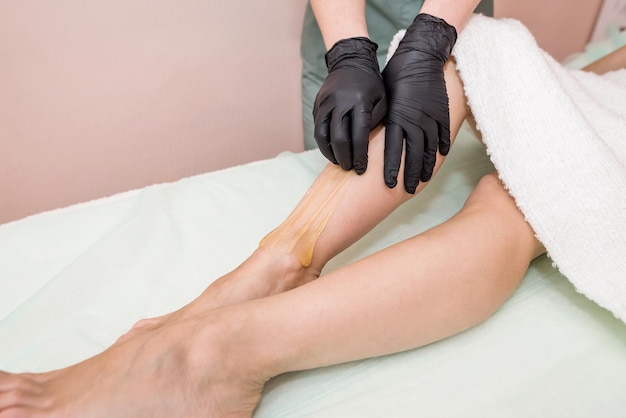 Hair removal at spa luxury studio Woman legs wax with sugaring Hot sugar