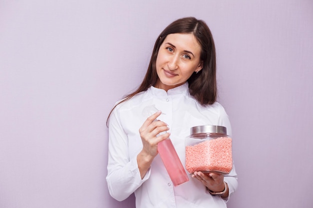 Hair removal specialist is holding wax in the jar and moisturizer in bottle beauty care product