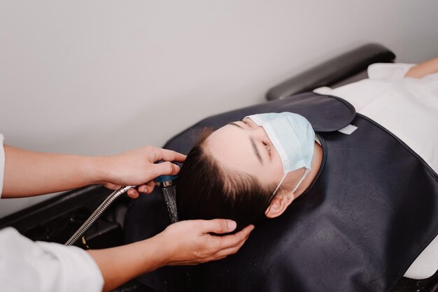 Hair salon concept a male hairdresser holding a water shower gently washing a female customers hair