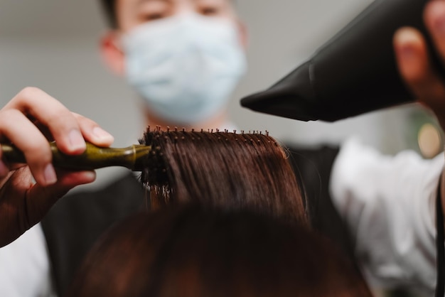 Hair salon concept a male hairstylist using a comb to grab a lock of hair and using hair drye