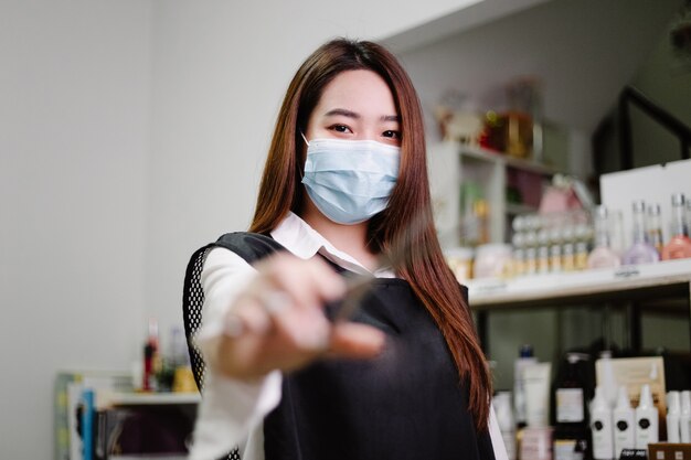 Hair salon concept a pretty hairdresser posing with scissers in a hand  in salon 