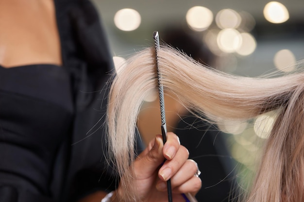 写真 ヘアスタイリストは、細いストランドにくしを使ってふっくらとした髪を作ります。