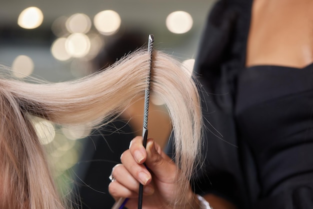 Hair stylist makes bouffant using comb on thin strands Shatush technique for hair lightening