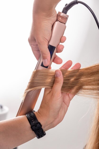 Hair stylist prepares woman makes curls hairstyle with curling iron