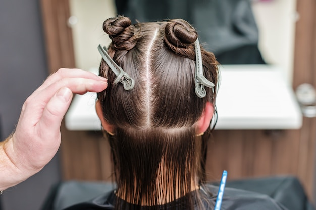 Hair stylist's hand divide women hair in sections with clips at hair salon.