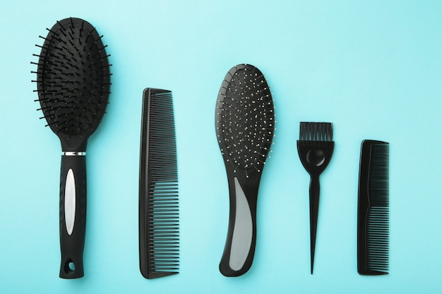 Инструменты для волос, концепция красоты и парикмахерского искусства - разные щетки или расчески на синей поверхности