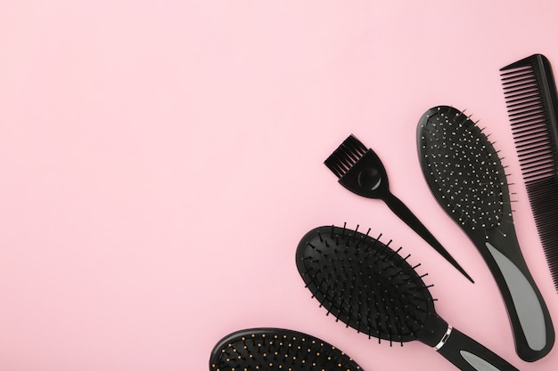 Hair tools, beauty and hairdressing concept - different brushes or combs on pink surface