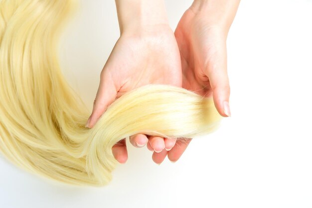 Haircare concept Female hand strokes blond hair