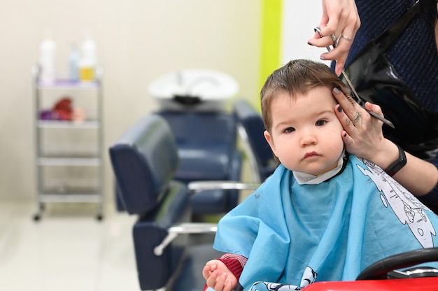 Haircut boy 0-1 years. The first haircut of the child at the hairdresser. Baby haircut toddler.