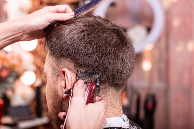 Haircut closeup. Hands holding a hair clipper.