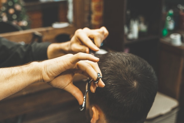 Haircut at the hairdresser. Barber cuts the hair on the client's head