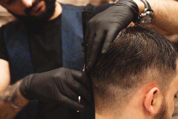 Testa di taglio di capelli nel barbiere, barber taglia i capelli sulla testa del cliente.