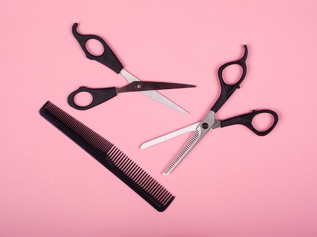 Haircutting tools, schaar en kam op een roze achtergrond.