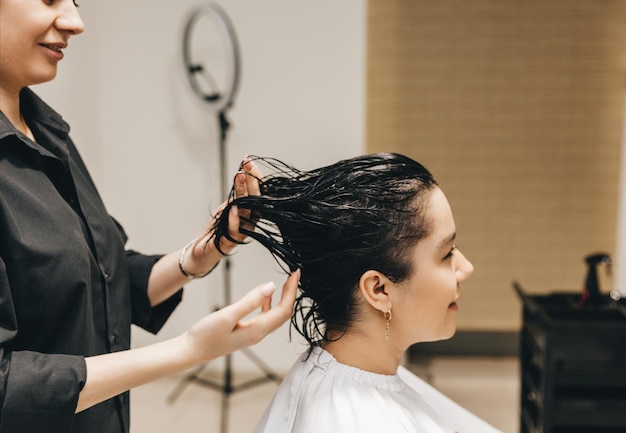 The hairdresser applies the gel on the hair of a woman in a beauty salon