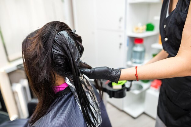 The hairdresser applies professional liquid keratin to the client's hair A girl does keratin hair strengthening in a beauty salon Hair care