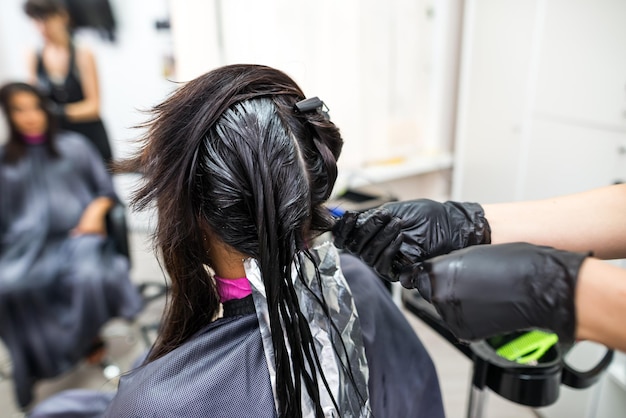 The hairdresser applies professional liquid keratin to the client's hair A girl does keratin hair strengthening in a beauty salon Hair care