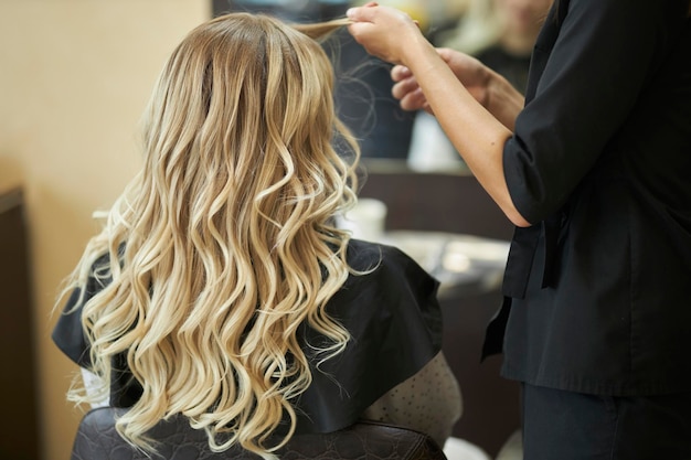 a hairdresser in a beauty salon doing hair styling to a client with a hair iron