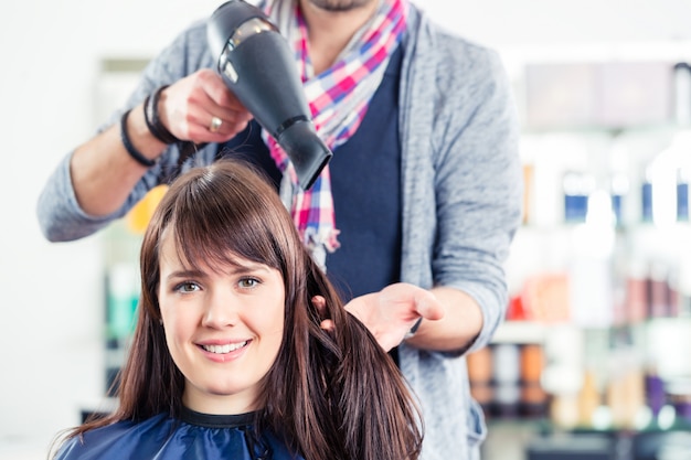 Hairdresser blow dry woman hair in shop