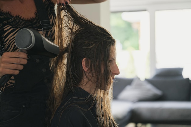 Hairdresser blow drying hair of a young woman