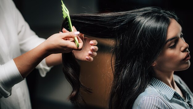 Photo hairdresser brushing womans long black hair