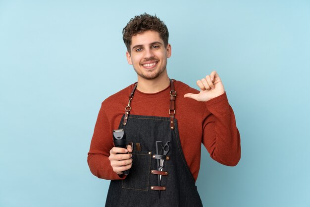 Hairdresser caucasian man on blue wall proud and self-satisfied