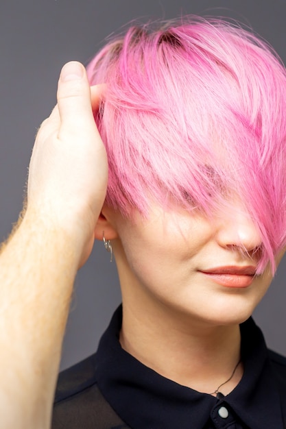 Hairdresser checking woman's pink hairstyle.