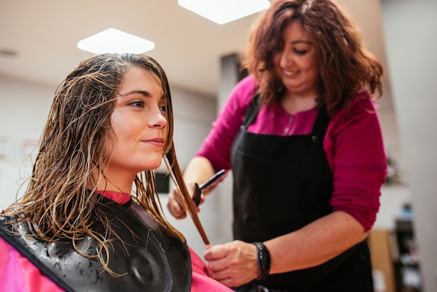 Hairdresser combing woman's hair