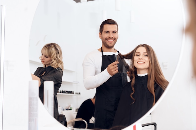 Hairdresser curling dark brown hair of beautiful woman.