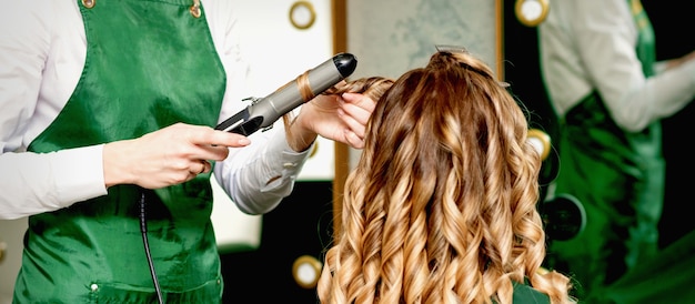 Hairdresser curling hair with curling iron