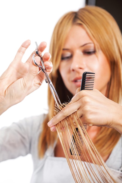 Hairdresser cut hair of a blonde woman