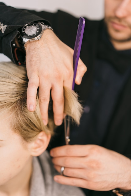 Hairdresser cut hair of woman. Man working as hairdresser and cutting hair of female customer