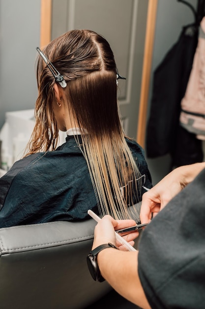 Foto un parrucchiere taglia i capelli di una bionda in un salone di bellezza taglio di capelli femminile