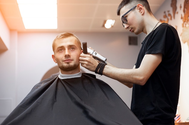 Hairdresser cuts a clients hair in a barbershop