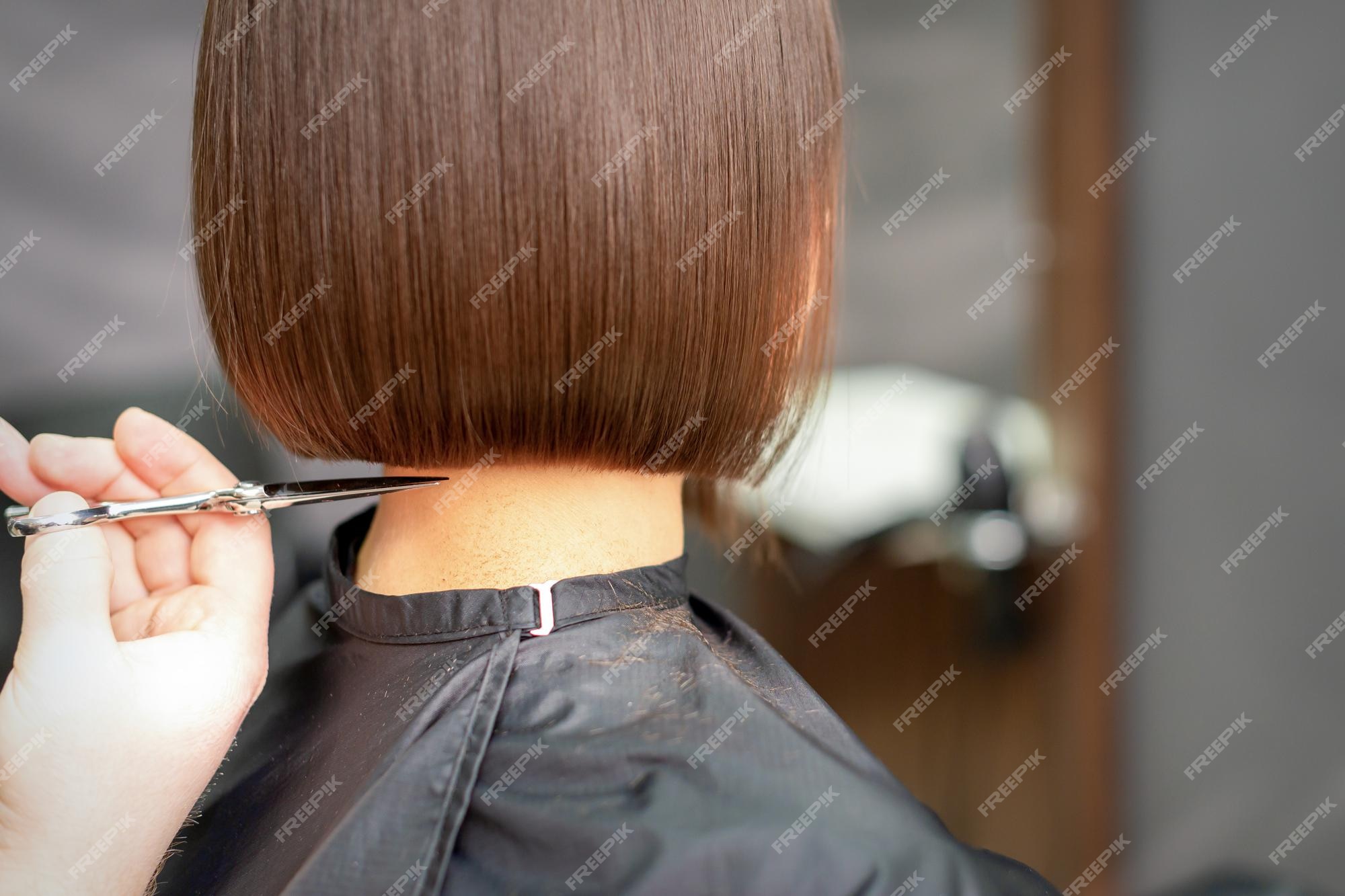 Premium Photo | The hairdresser cuts the hair of a brunette woman.  hairstylist is cutting the hair of female client in a professional hair  salon, close up.