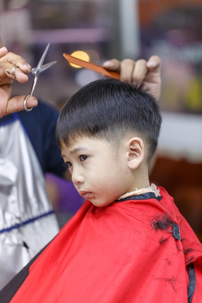 Photo hairdresser cutting boy hair in salon