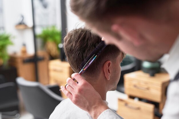 Foto parrucchiere che taglia i capelli di un cliente maschio nel salone