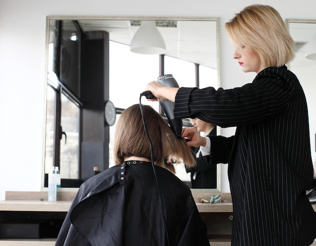 Парикмахер стрижет волосы в салоне крупным планом