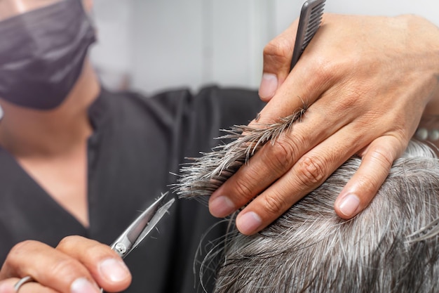 The hairdresser cutting hair of a senior