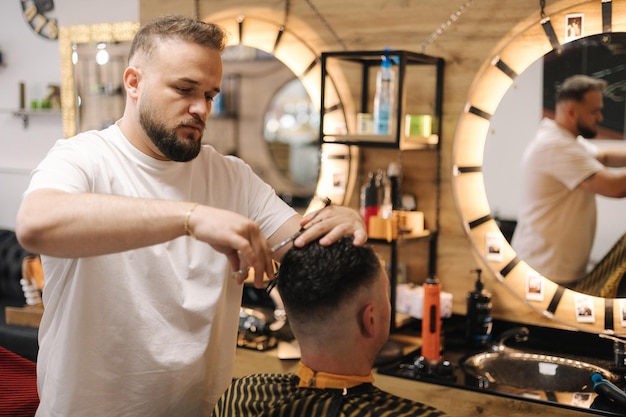 Hairdresser cutting hair using scissors and comb professional barber serves the client