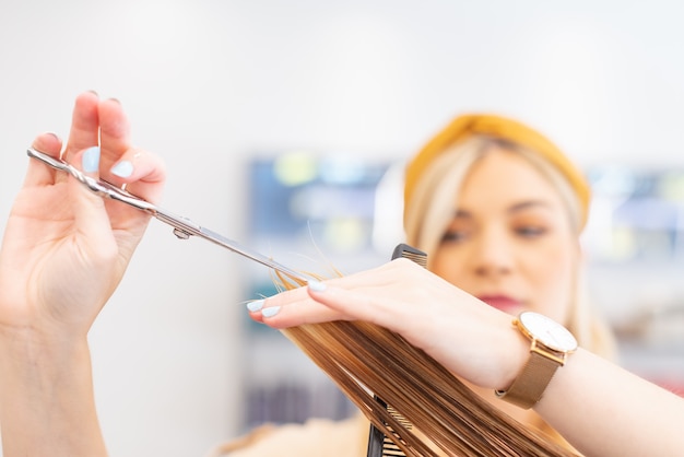 Hairdresser cutting hair with scissors to a caucasian client in her hairdresser CSelective focus