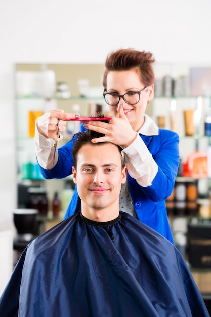 Hairdresser cutting man hair in barbershop