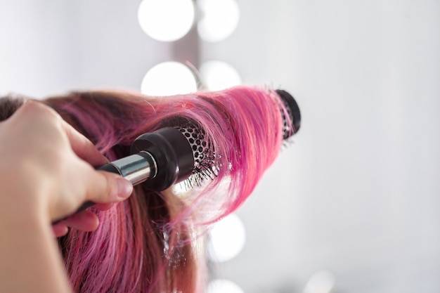 Hairdresser does hair style of woman