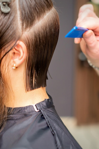 Foto parrucchiere che fa taglio di capelli di giovane donna