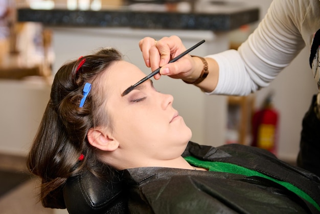 hairdresser doing makeup and styling a young female client in a beauty salon