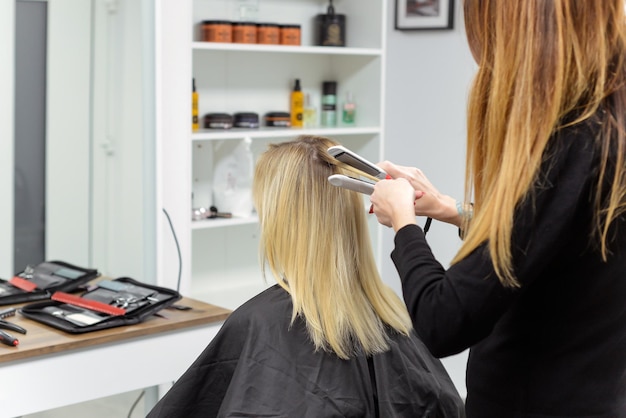 hairdresser doing stylish styling to woman in salon