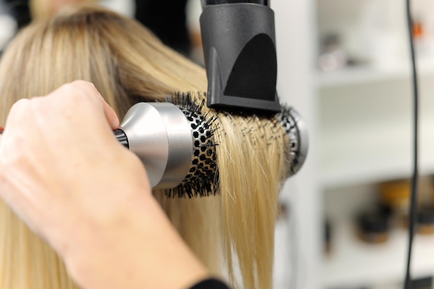 hairdresser dries hair with a hairdryer to a woman after a haircut in the salon