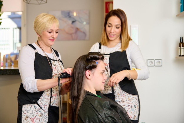 Il parrucchiere asciuga e acconcia i capelli con un asciugacapelli nel salone di bellezza