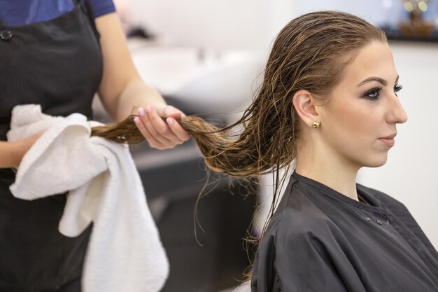 The hairdresser dries the washed hair to a beautiful young woman at the hairdresser