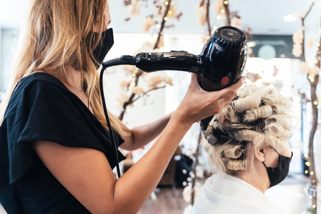 Hairdresser drying a client's hair while giving a perm