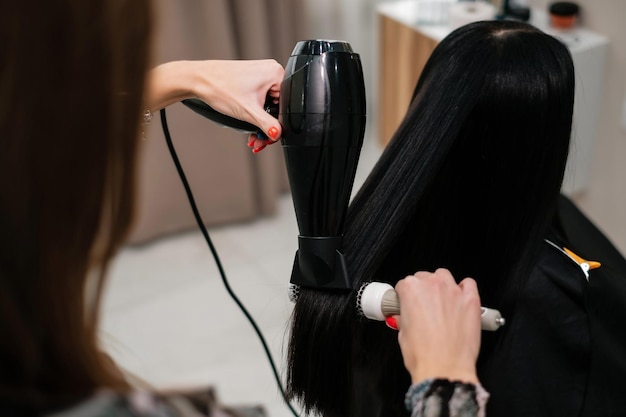 Hairdresser drying and combing black hair